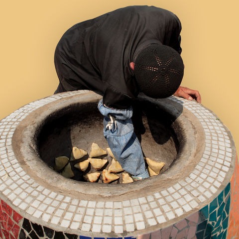 Mann backt Samosa in traditionellem Ofen, Tadschikistan